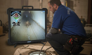 A Drainiacs Plumbing technician using a sewer camera monitor to inspect a main sewer line in a Clifton basement.